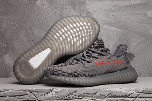 Pair of dark grey and black patterned Yeezy 350 V2-style sneakers showing the ribbed outsole and red side lettering.