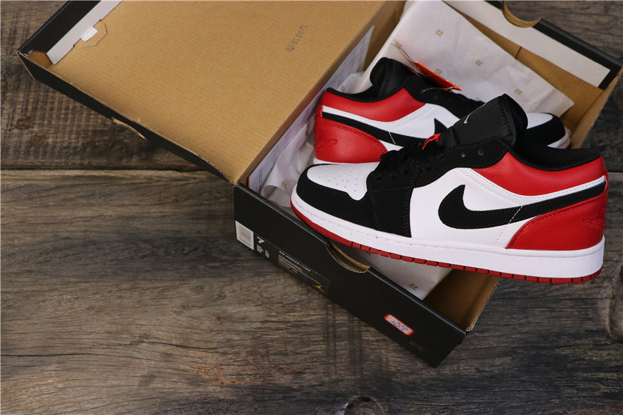 Pair of black, white, and red low-top sneakers displayed in an open black shoe box.