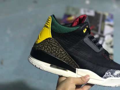 Close-up side view of a black Jordan 3-style sneaker with patterned heel overlay, green collar, and yellow heel accent.