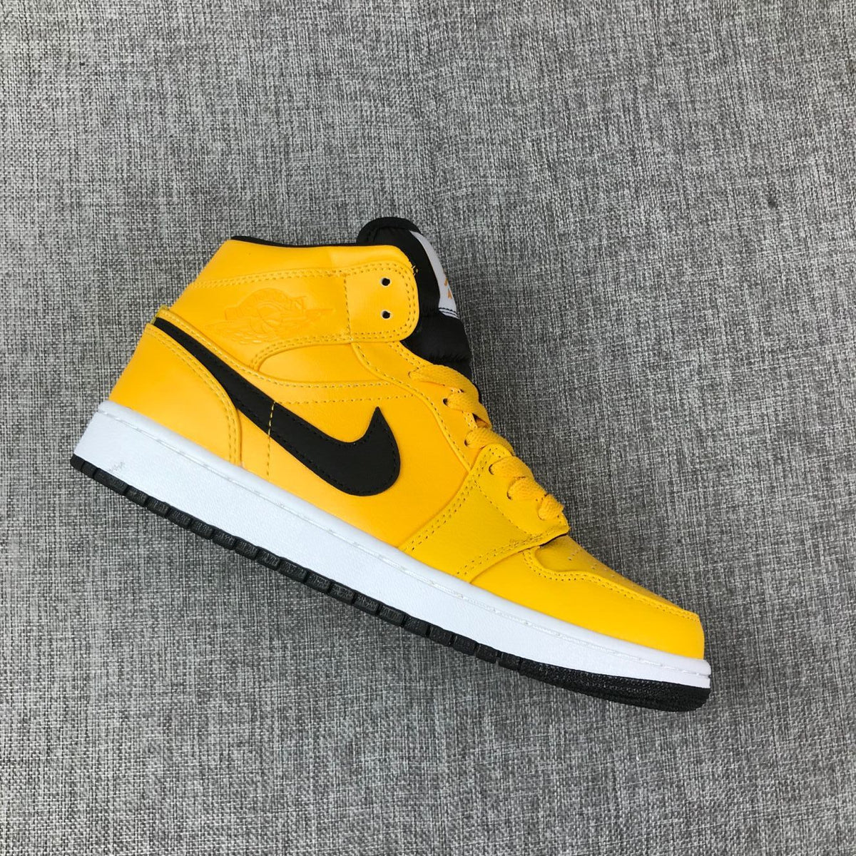 Single side profile showing the yellow upper, black branding, white midsole, and black outsole.