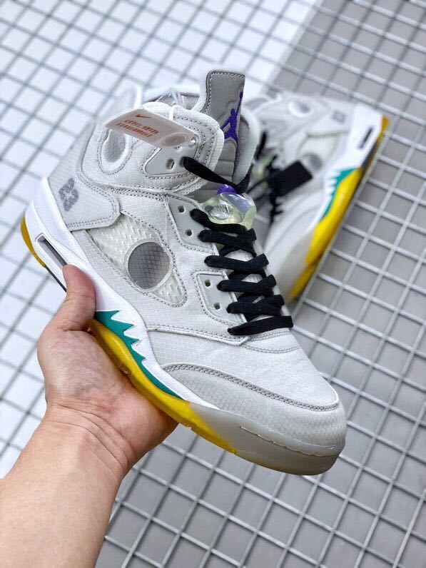Front three-quarter view showing the grey upper, black laces, translucent details, and colored outsole accents.