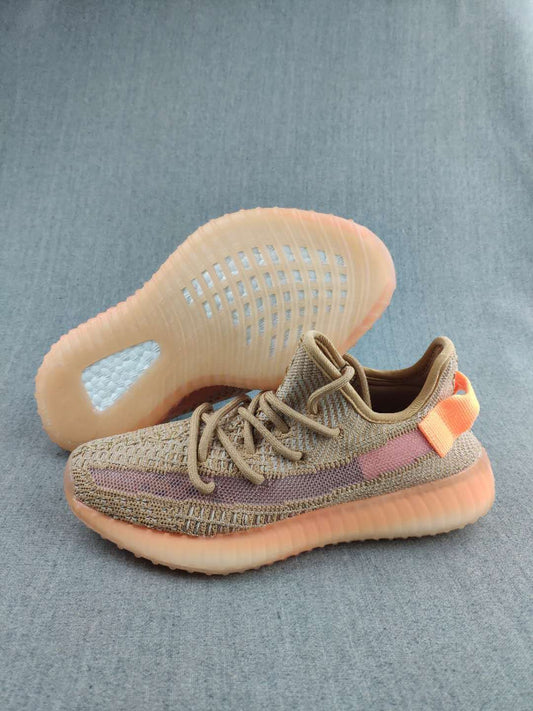 Pair of tan Yeezy 350 V2-style sneakers showing the mauve side stripe, orange heel accents, and translucent amber-toned soles.
