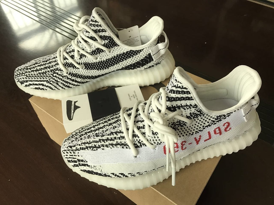 Pair of black-and-white patterned knit sneakers displayed on a shoe box in daylight.