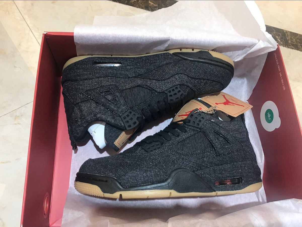 Pair of black sneakers displayed inside a red shoe box.