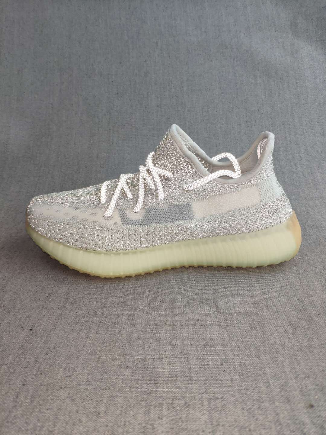 Side profile of the silver and white sneaker with a translucent yellow-toned sole.
