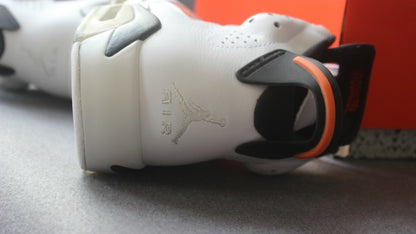 Close-up of the heel showing the white upper, black pull tab, orange accent, and embroidered Jumpman detail.