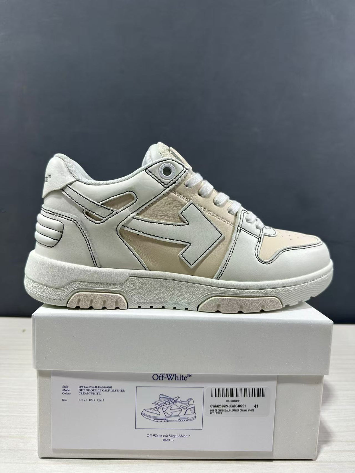 Side view of a cream-white sneaker above its product box; the box label identifies the model and shows size EU 41.