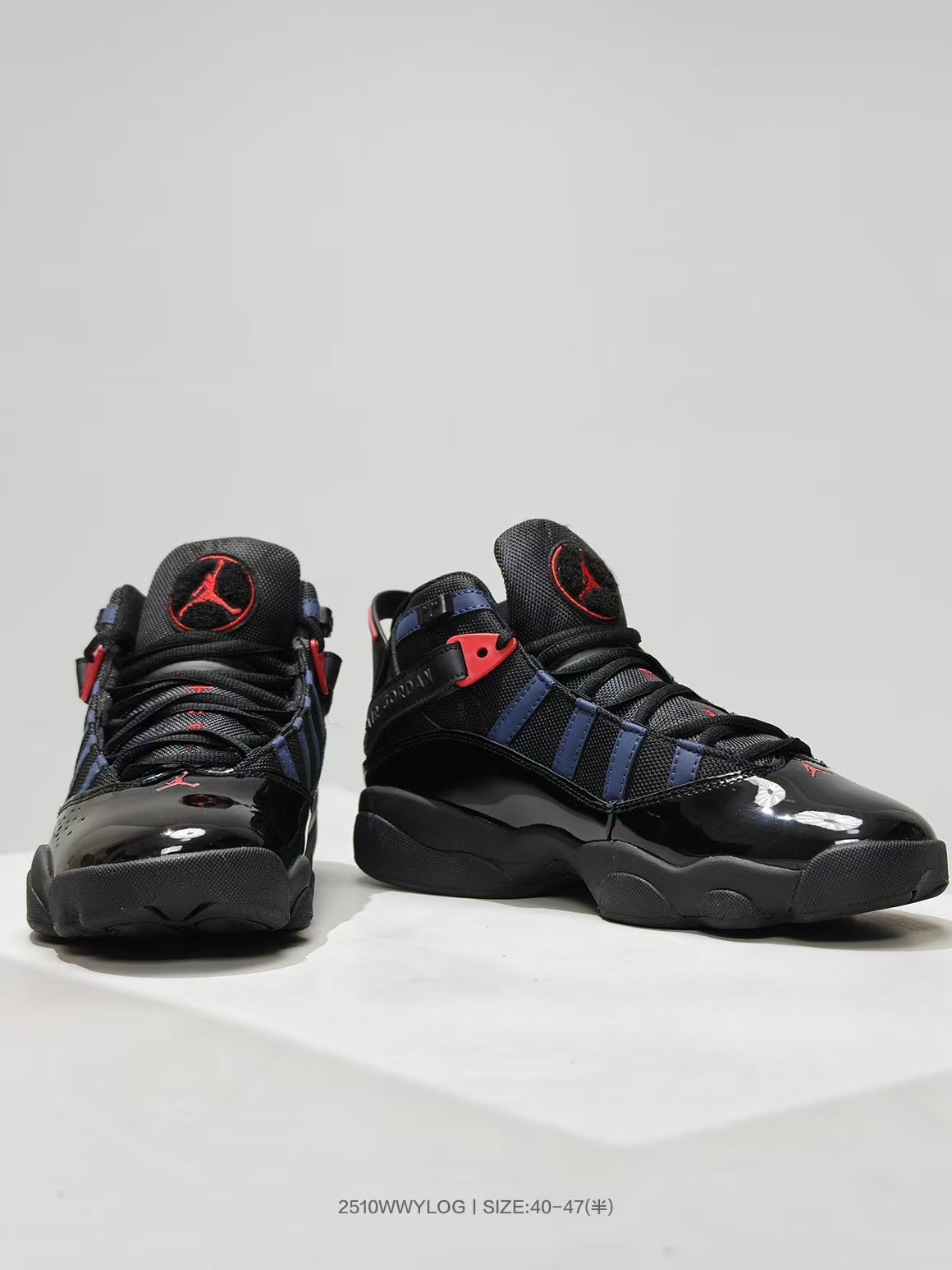 Front three-quarter view of black high-top sneakers with navy side panels, red accents, and glossy toe areas.
