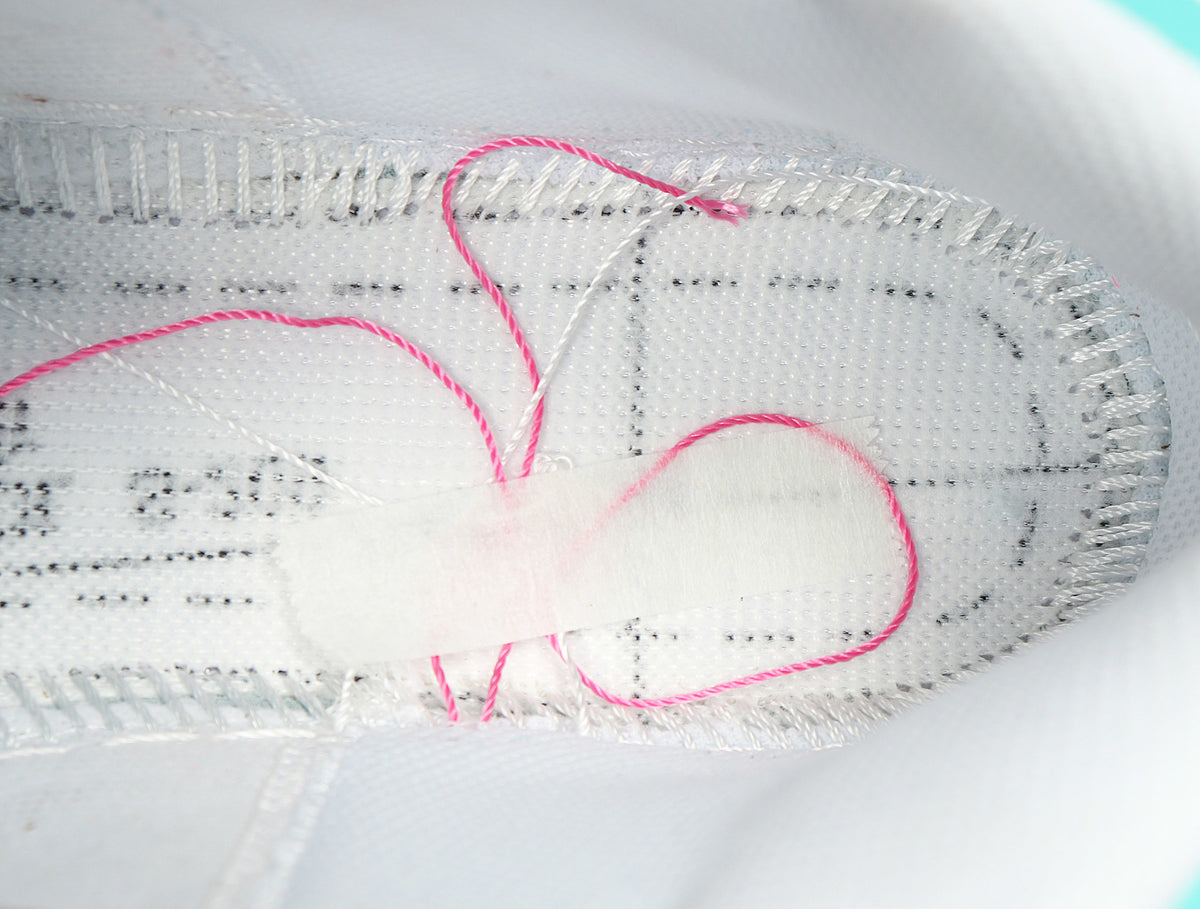 Close-up of the white shoe interior showing stitched lining and pink-and-white detailing.