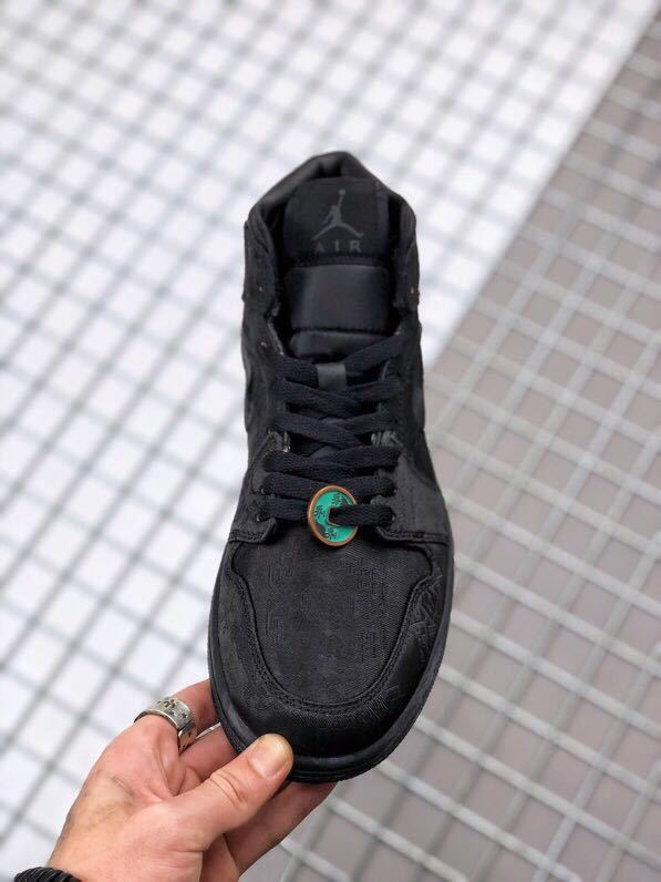 Top-down view of the black sneaker showing the laces, tongue, and patterned toe box.