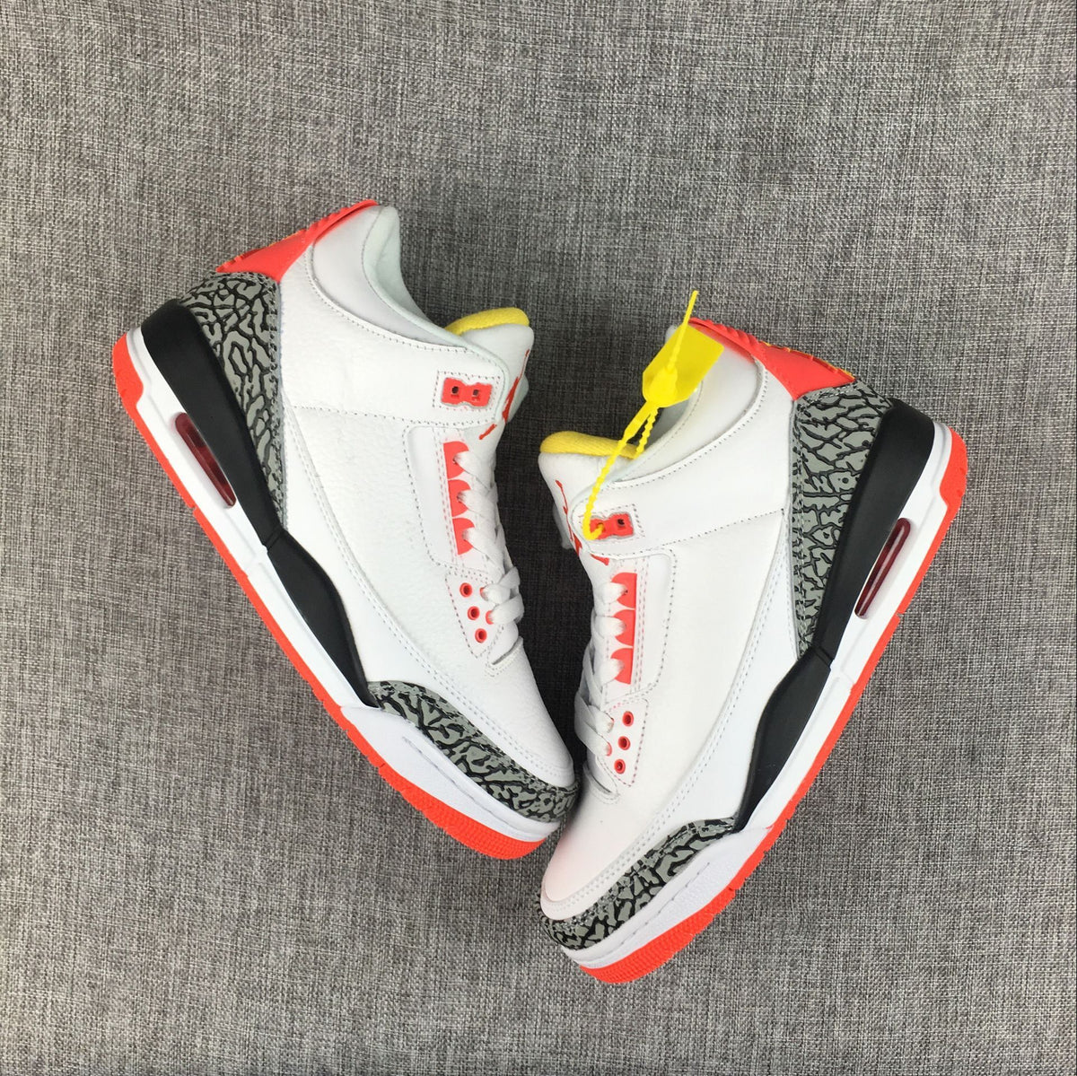 Pair of white Jordan 3 sneakers shown from above with red, yellow, and black details.