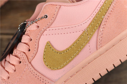 Close-up of the coral pink sneaker side showing the gold-toned swoosh-style side emblem, stitching, laces, and textured midsole.