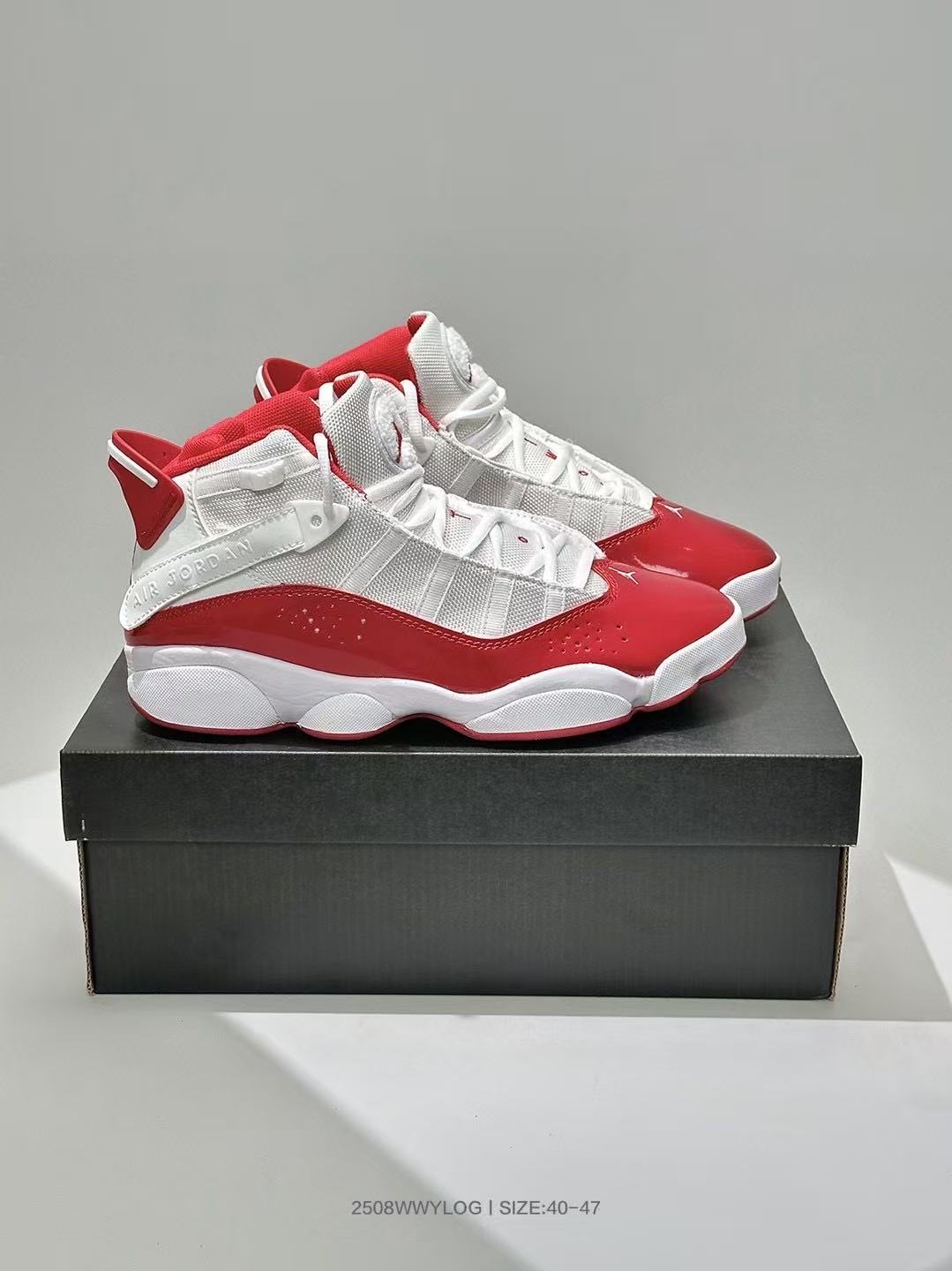 Side view of the pair displayed on a dark shoe box, showing the layered upper and white-red color blocking.