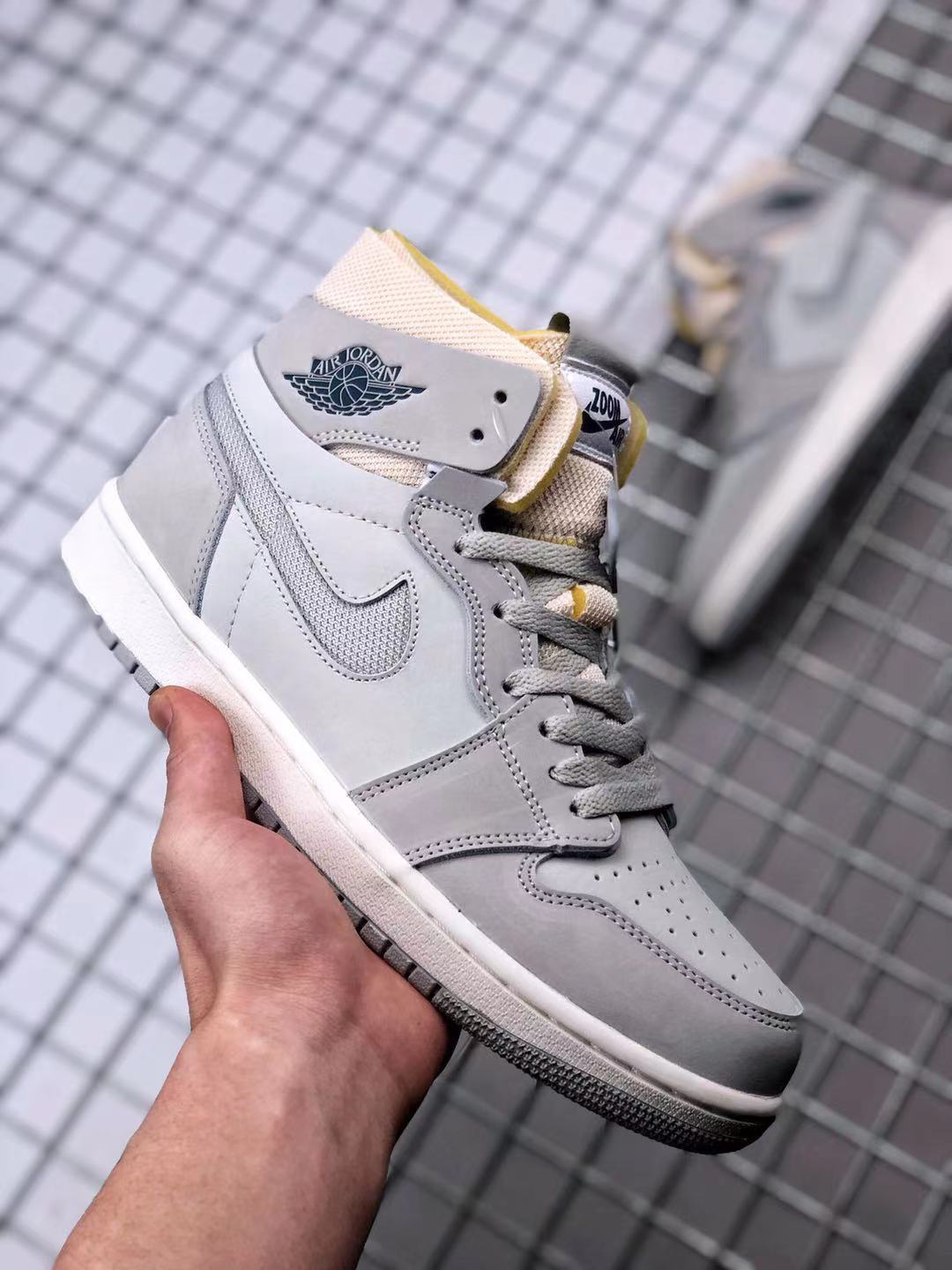 Front three-quarter view of the gray high-top sneaker with gray laces, perforated toe box, and yellow accents.