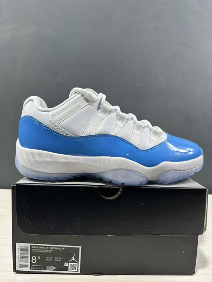 Side view of white and blue Jordan Air Jordan 11 Retro Low sneakers displayed on a black shoe box; the box label shows EU 42 and style code FV5104 100.