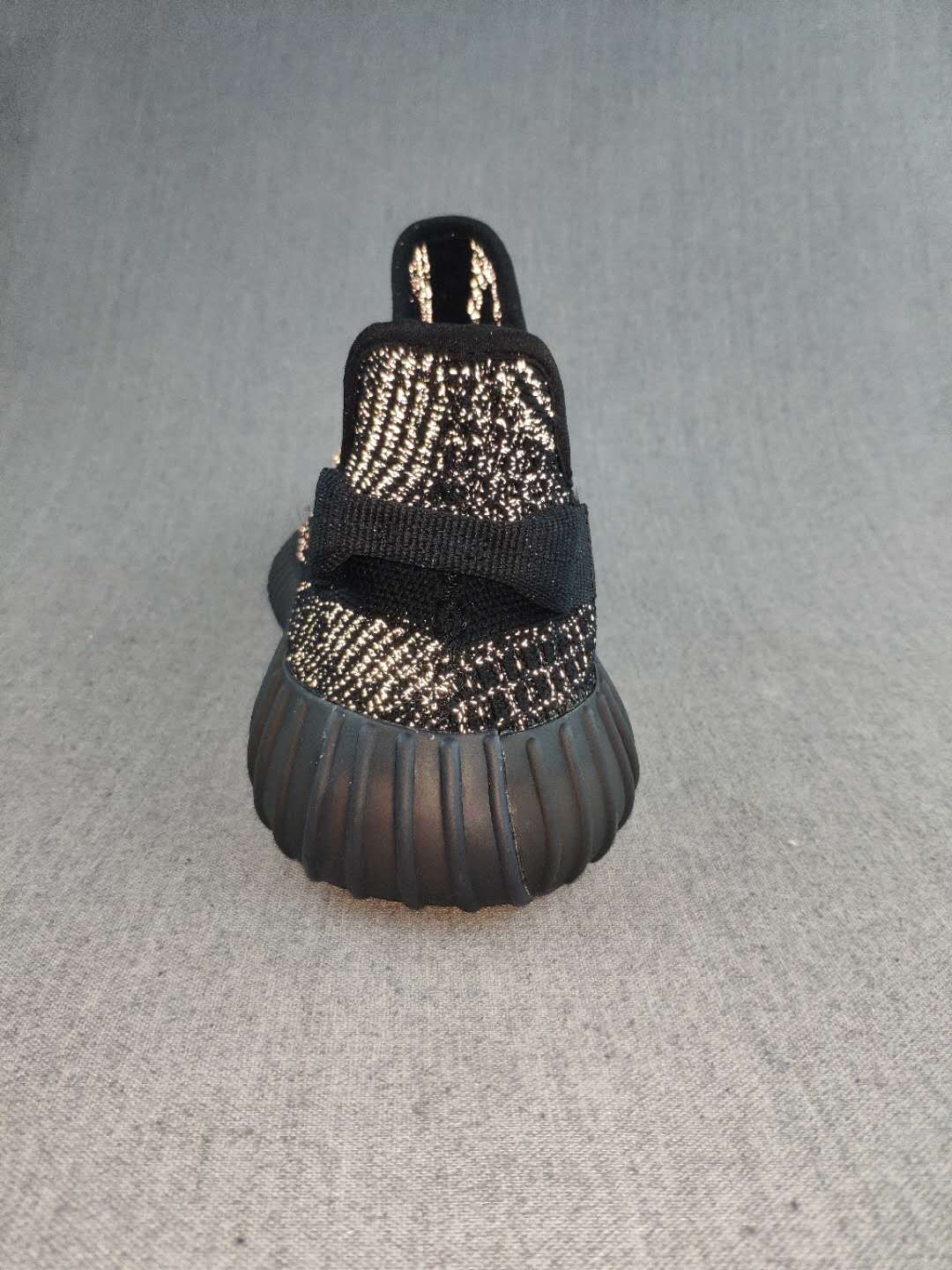 Rear view of a black sneaker showing the pull tab, heel construction, and ribbed outsole.