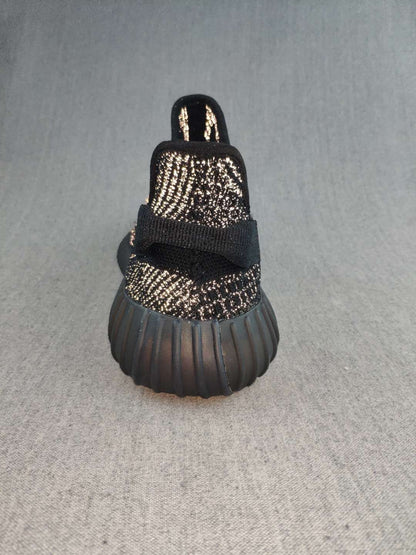 Rear view of a black sneaker showing the pull tab, heel construction, and ribbed outsole.