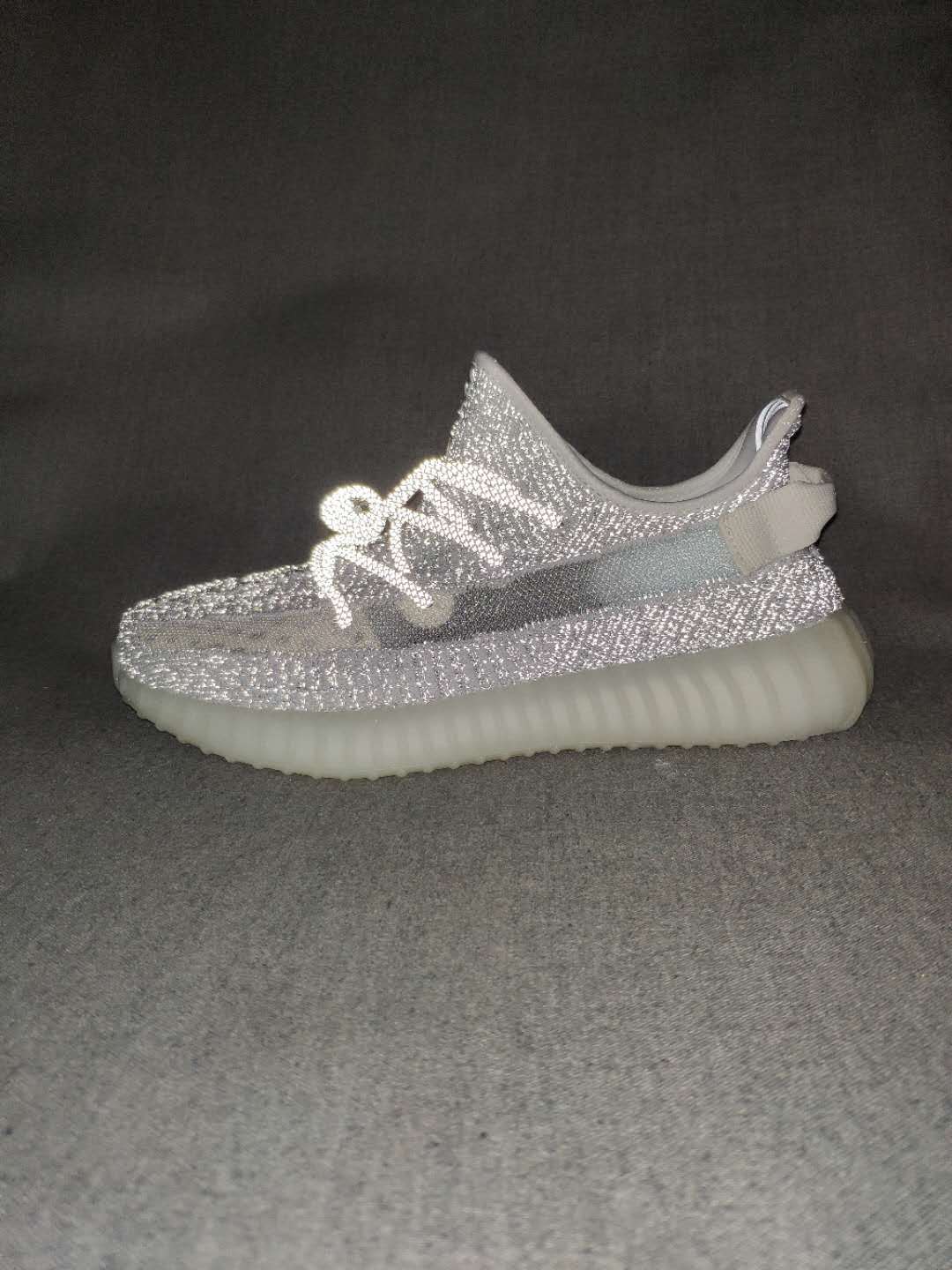 Side profile of the silver-gray sneaker showing the outer stripe, low-top shape, and ribbed translucent sole.