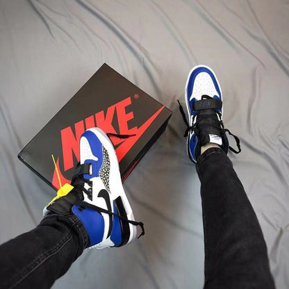 Overhead view of the sneakers being worn beside a branded shoebox, showing the blue, white, and black color blocking.
