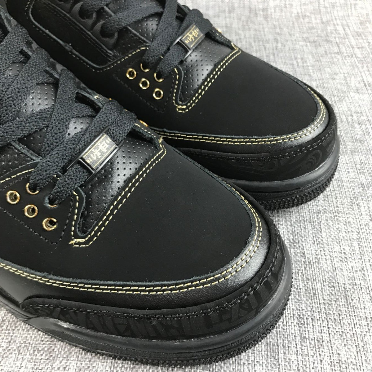 Three-quarter view of the pair showing black uppers and gold details