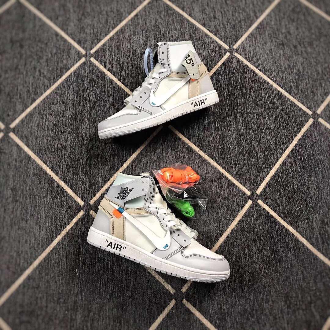 Two grey and white high-top sneakers displayed with orange and green spare laces.