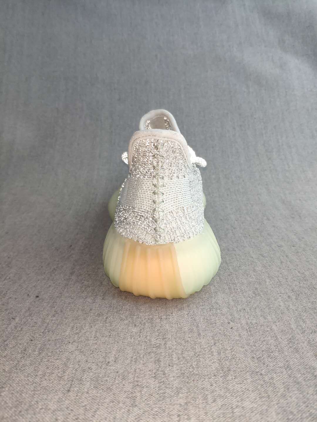 Rear view of the silver and white sneaker with a ribbed translucent outsole.