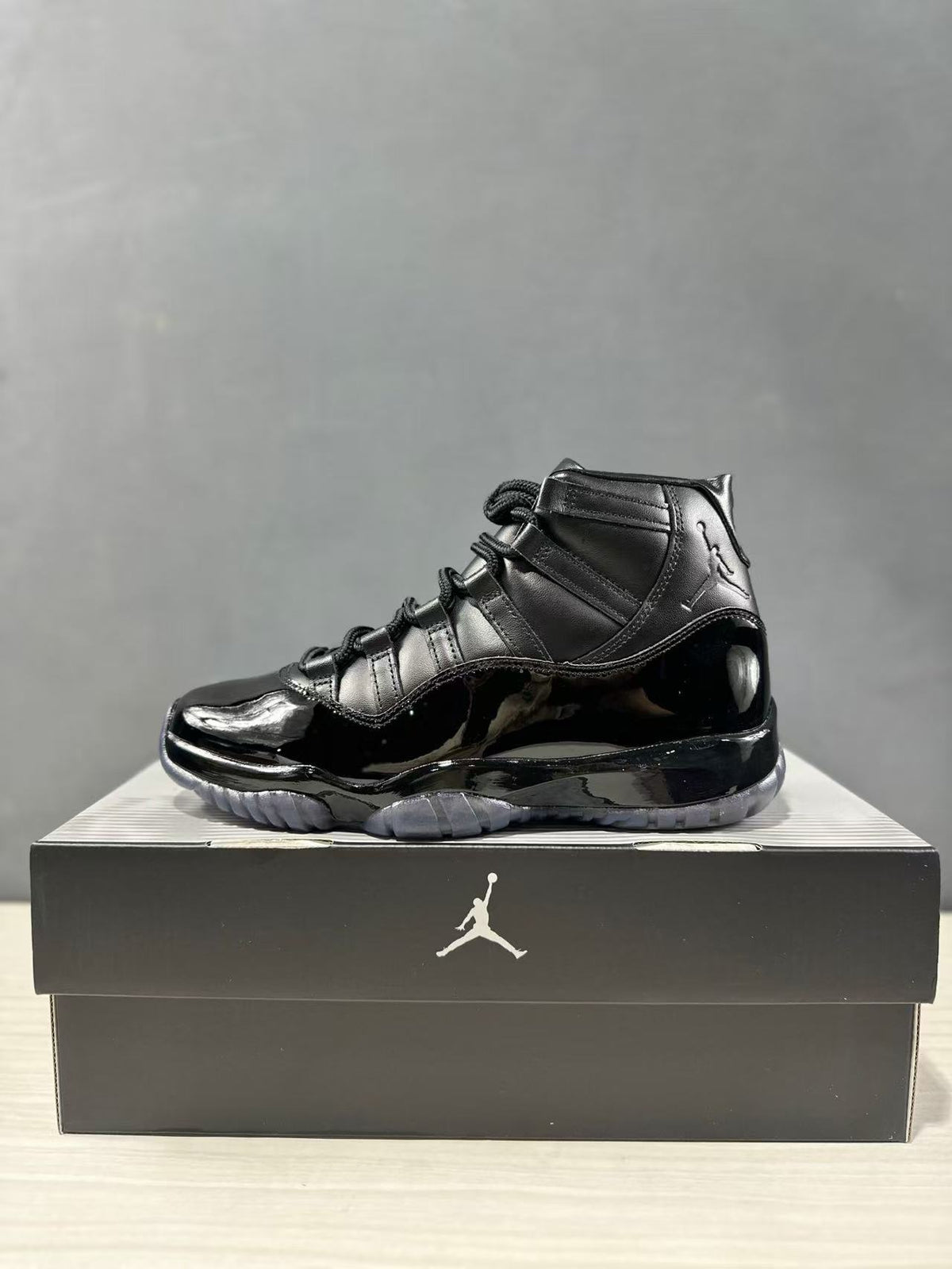 Side profile of a black high-top sneaker with black laces, Jordan upper branding, and a glossy lower section.