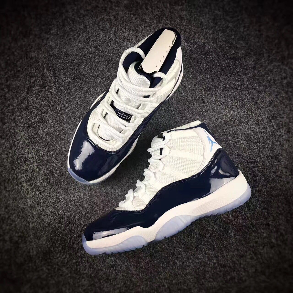 Pair of sneakers displayed at an angle, showing the lacing layout, navy overlays, and white uppers.