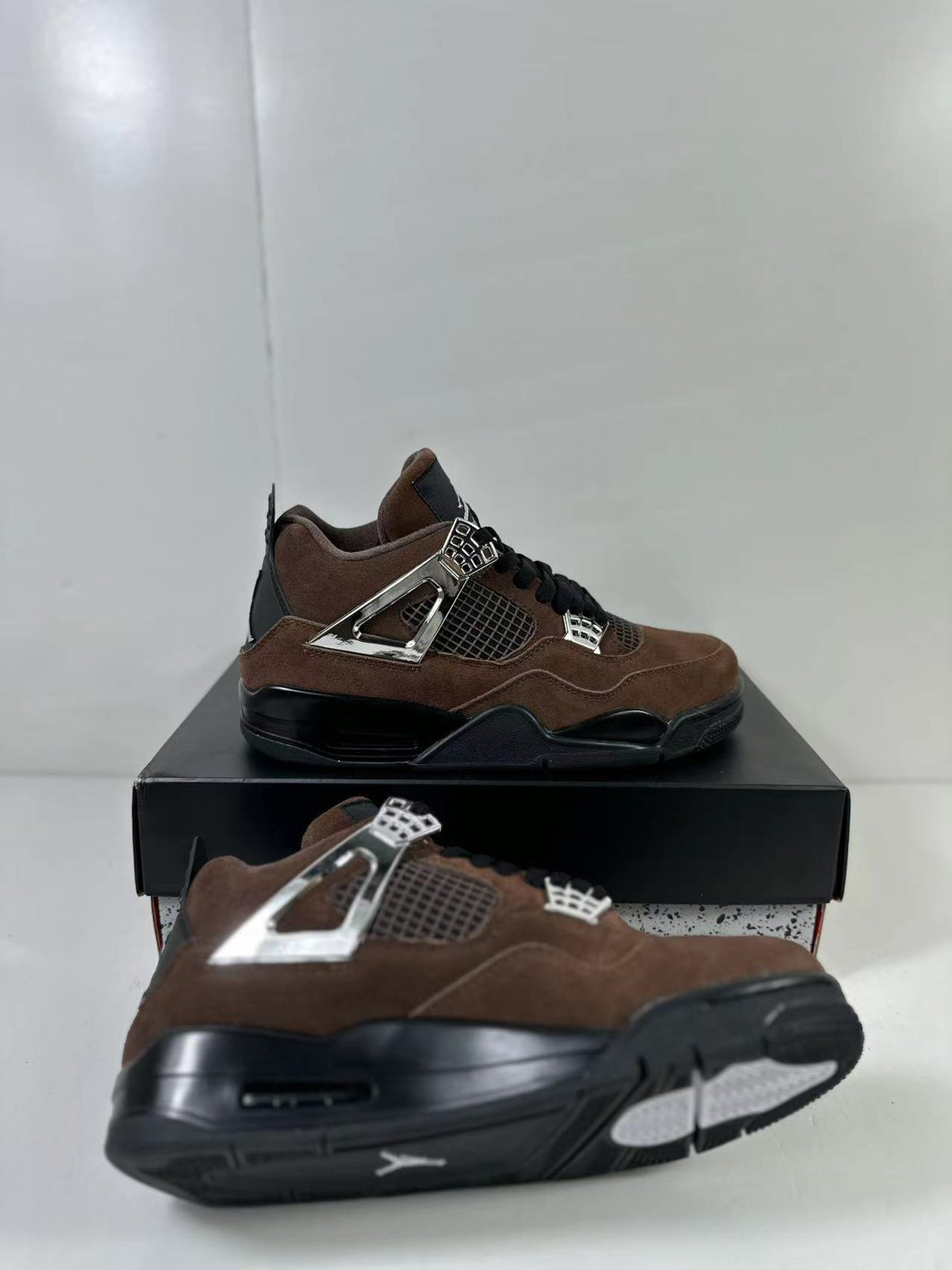 Angled view showing the brown upper, black sole, mesh panels, and metallic-tone side hardware.