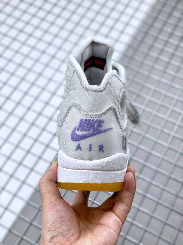 Rear view of the grey and white sneaker showing purple Nike Air branding and a yellow outsole edge.