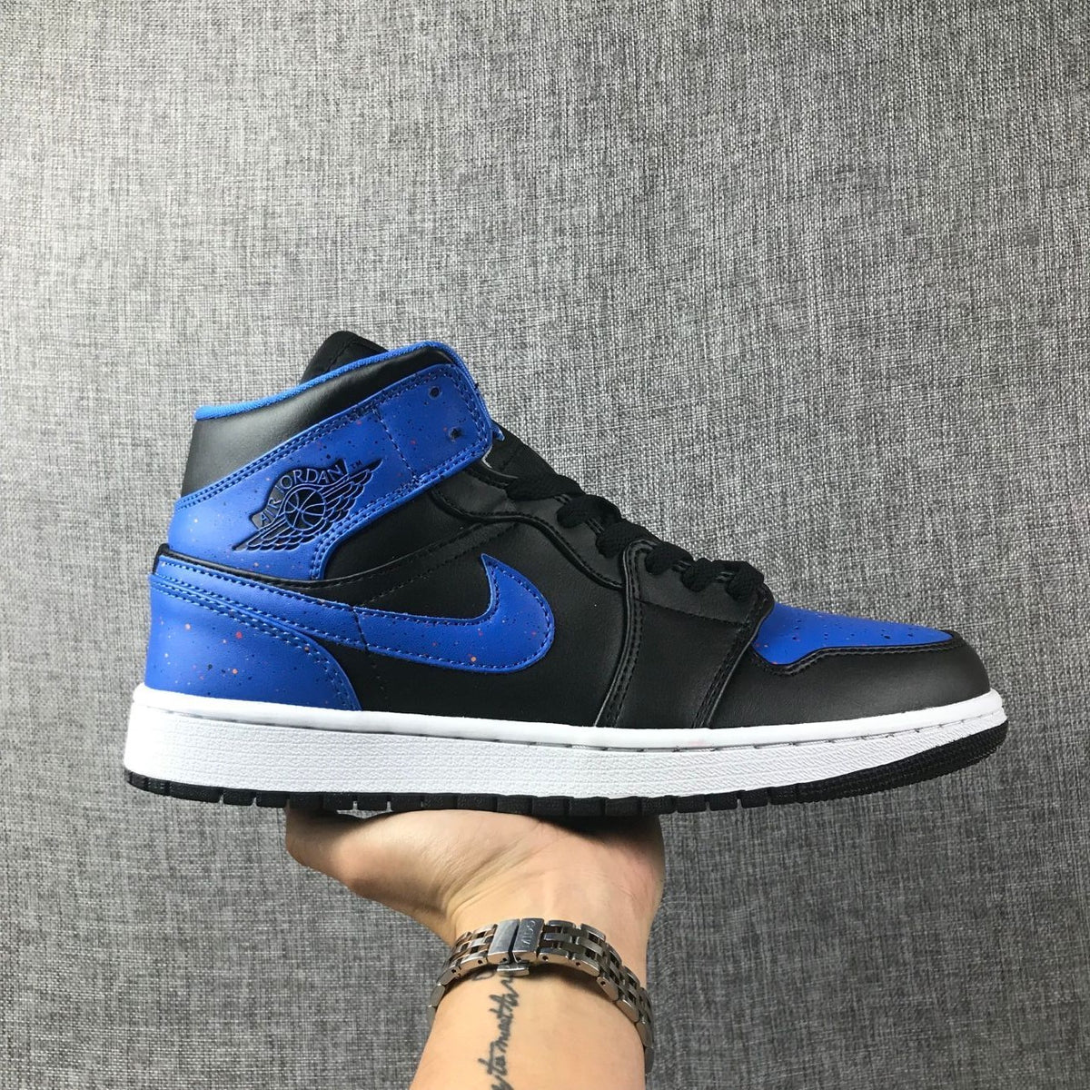 Side profile of a black and blue high-top Jordan sneaker with a white midsole.
