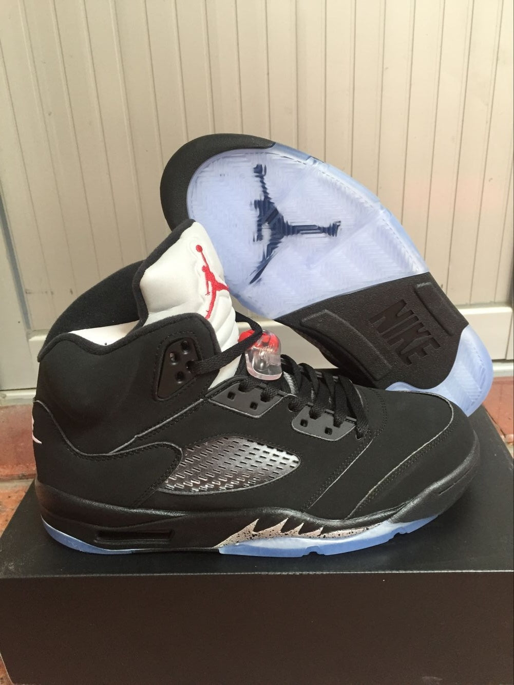 Black and silver high-top sneaker shown from the side with a translucent blue outsole and silver side panel.