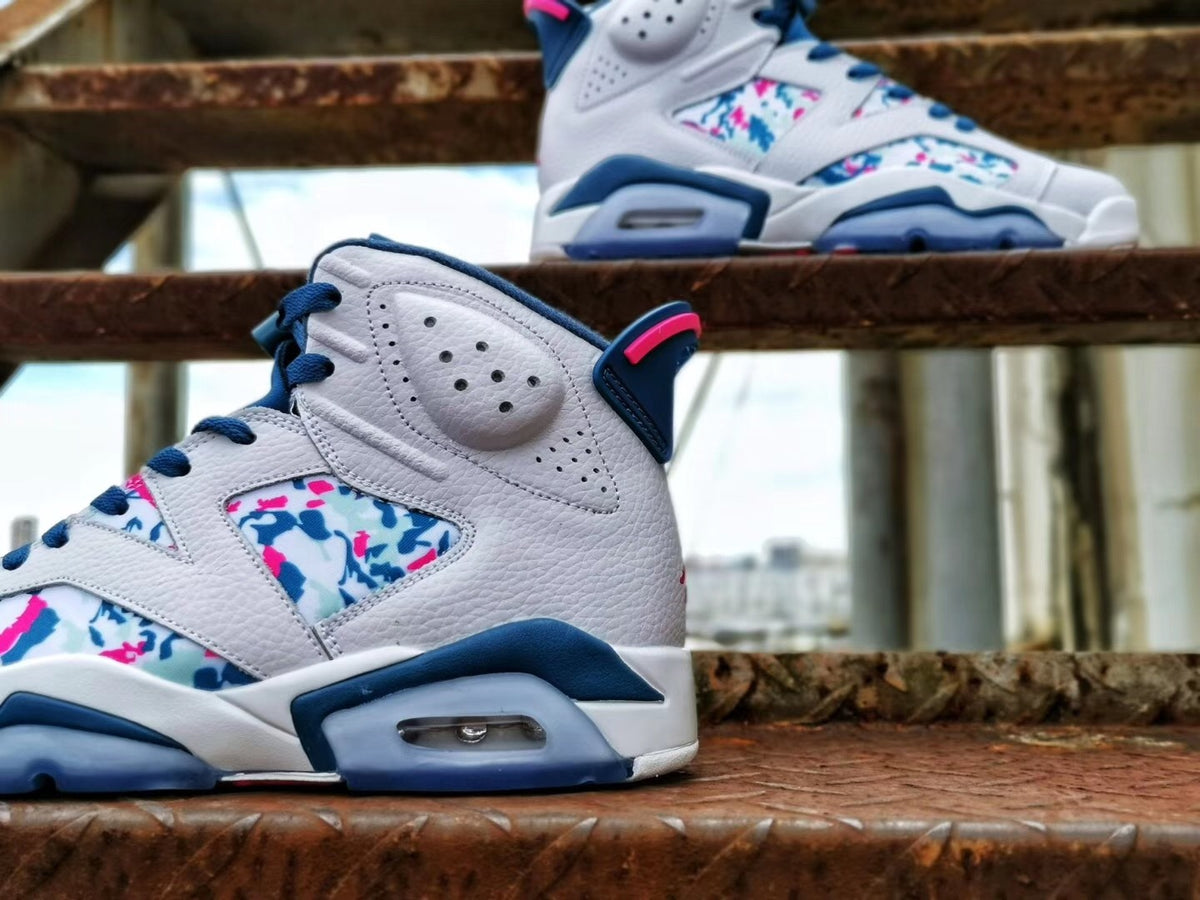 Side view highlighting the perforated white upper, multicolor patterned panels, blue midsole accents, and visible heel air unit.
