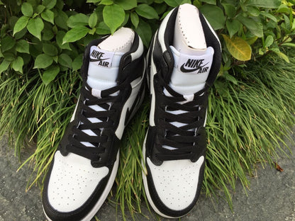 Front view of a pair of black and white high-top sneakers with branded tongue labels and contrasting laces.