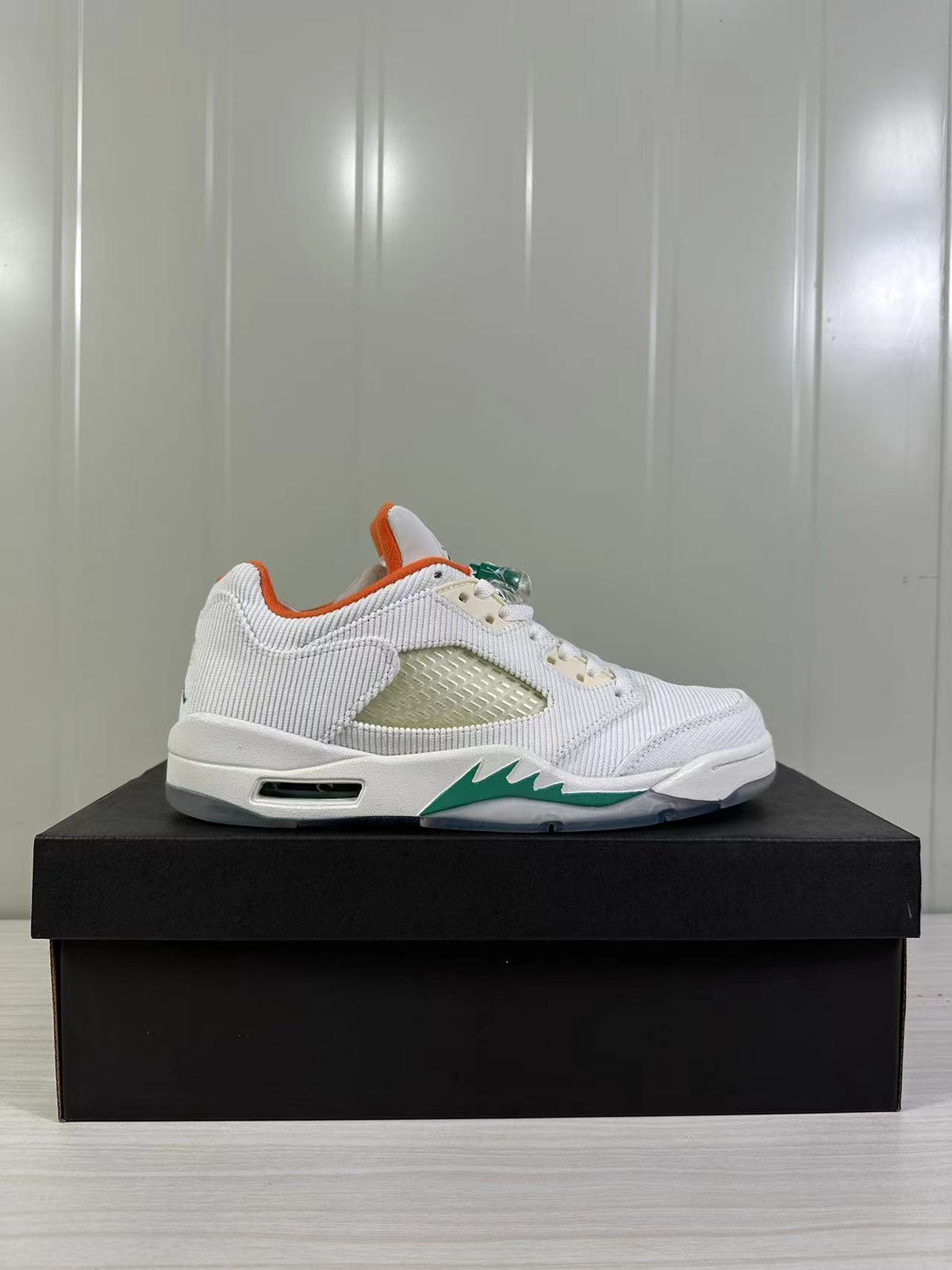 Side profile showing the white upper, orange collar lining, green midsole accent, and outsole detail.