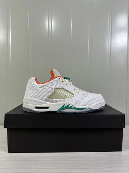 Side profile showing the white upper, orange collar lining, green midsole accent, and outsole detail.
