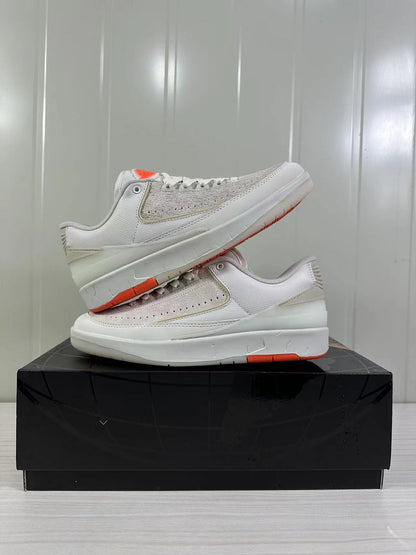Displayed pair of low-top sneakers showing the beige and white color scheme and orange outsole accents.