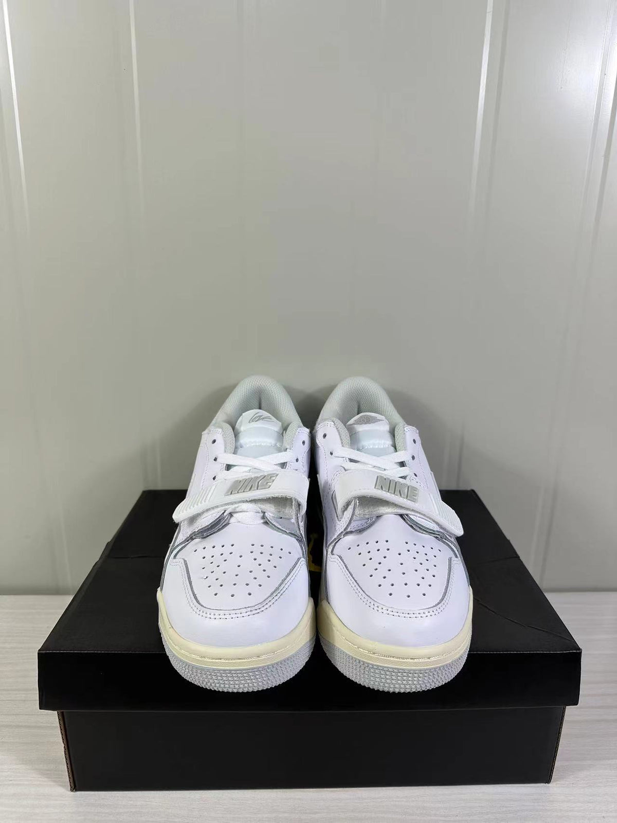 Pair of predominantly white Jordan Legacy 312 Low sneakers shown from the front on a black shoe box.