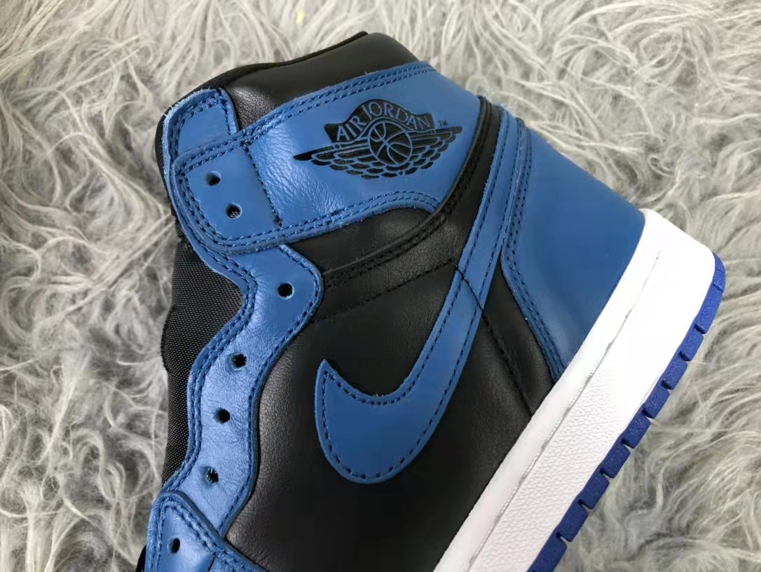 Close-up of a black and blue high-top sneaker showing the Air Jordan winged emblem, blue Swoosh, stitched panels, and white midsole.