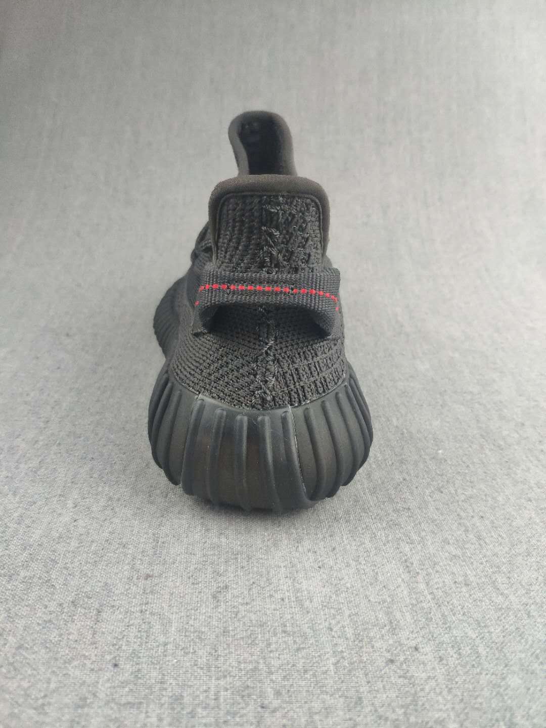 Rear view of a black sneaker showing the heel pull tab and ribbed outsole.