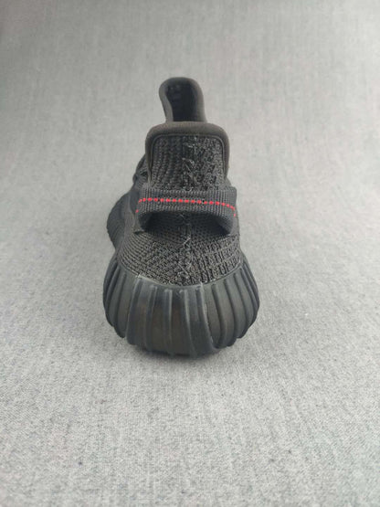 Rear view of a black sneaker showing the heel pull tab and ribbed outsole.