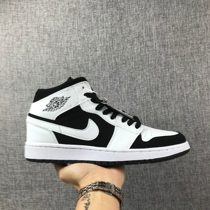 Side view of a black-and-white Jordan Air Jordan 1 Mid sneaker held against a gray fabric background.
