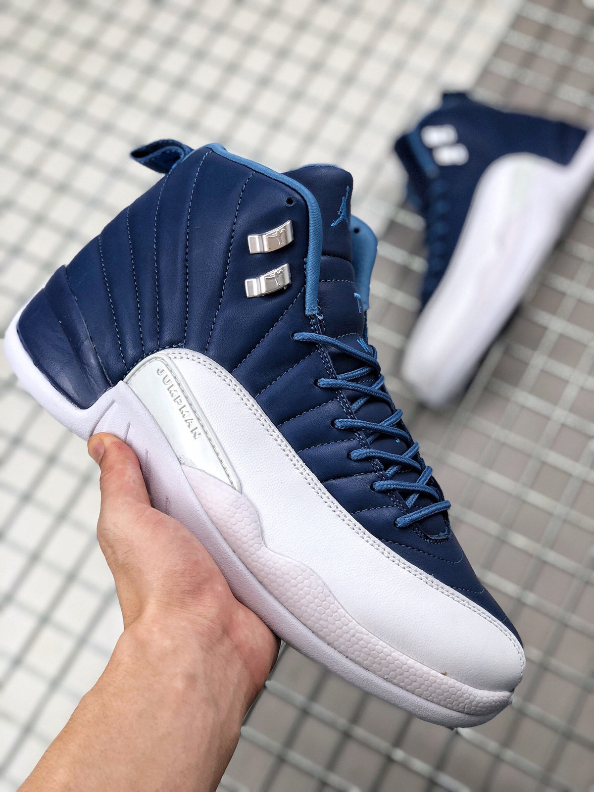 Angled side view showing the dark indigo upper, white side panel, stitched detailing, and metallic lace hardware.