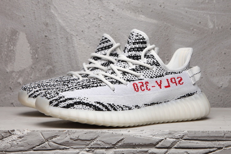 Pair of black-and-white patterned sneakers shown from a side angle with white laces and translucent ribbed soles.