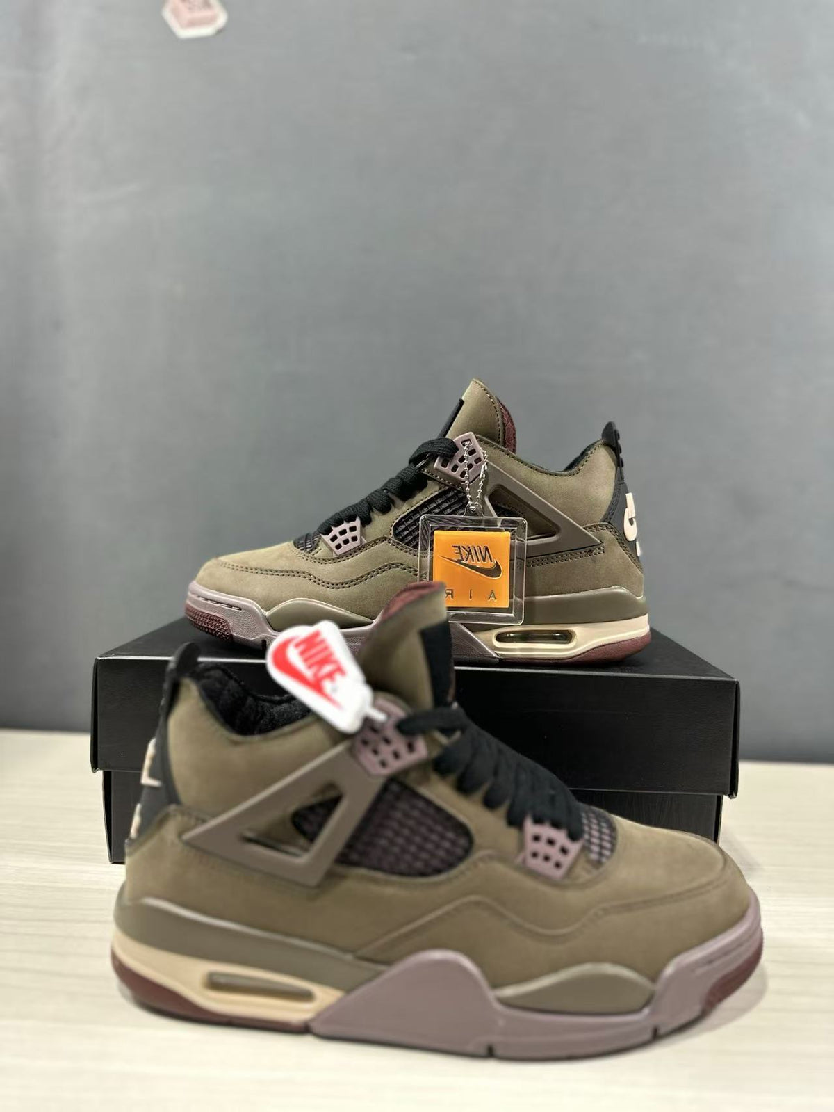 Three-quarter view of the sneakers with a clear branded hangtag and black shoebox.