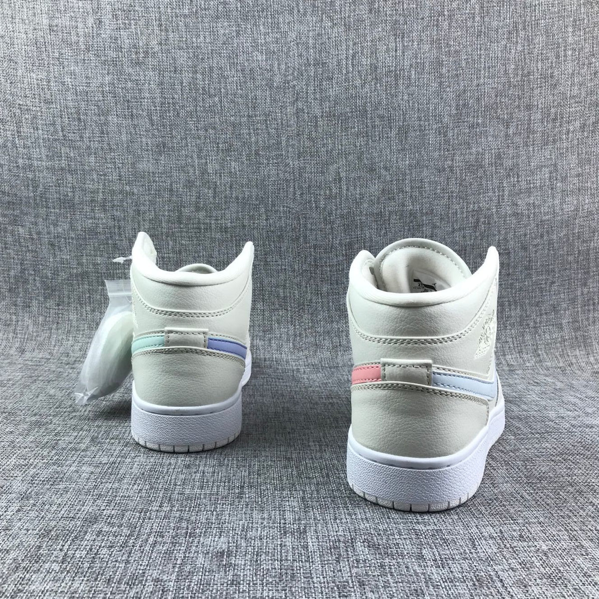 Rear view of the pair showing pastel accent strips across the heels and white rubber outsoles.