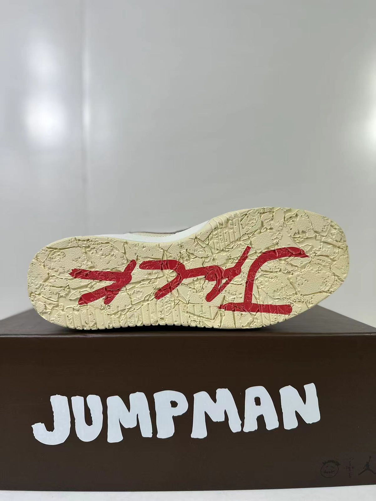 Bottom view of the cream outsole with red graphic detailing and a textured tread pattern.
