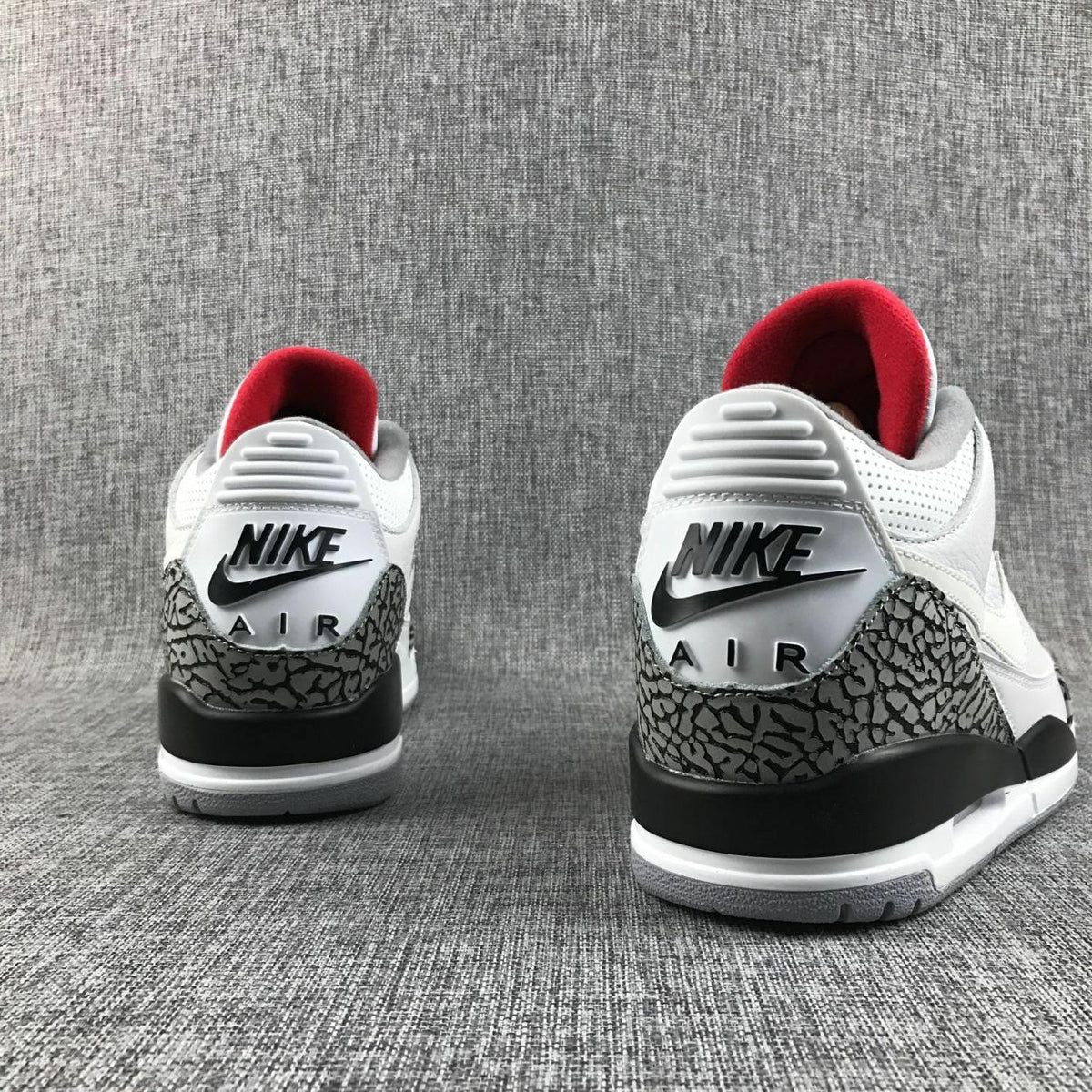 Rear view of the pair showing Jordan branding, grey elephant-print heel overlays, and red inner collars.