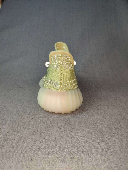 Rear view of the green sneaker showing the heel pull tab, woven-looking upper, and rounded translucent sole.