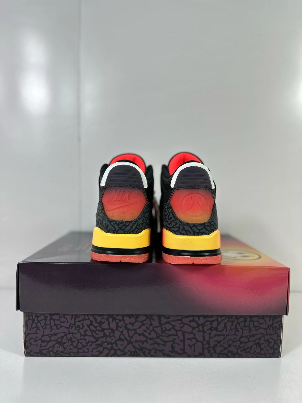 Rear view of the pair showing red-to-orange heel details, elephant-print panels, and yellow midsole sections.